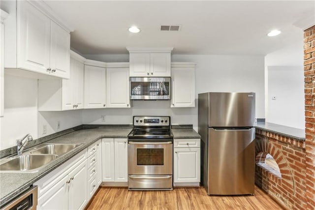 869 Briarcliff Rd NE Unit B25, Atlanta, GA 30306 - kitchen with appliances with stainless steel finishes, light wood-type flooring, white cabinetry, and a sink