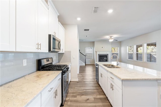 kitchen with white cabinetry, stainless steel appliances, sink, and light stone counters