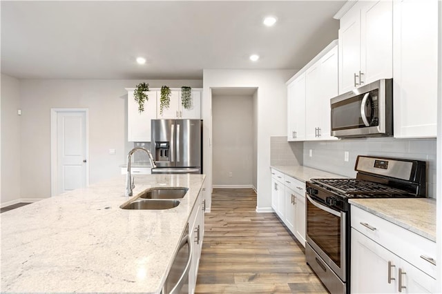 kitchen with white cabinetry, appliances with stainless steel finishes, light stone countertops, and sink