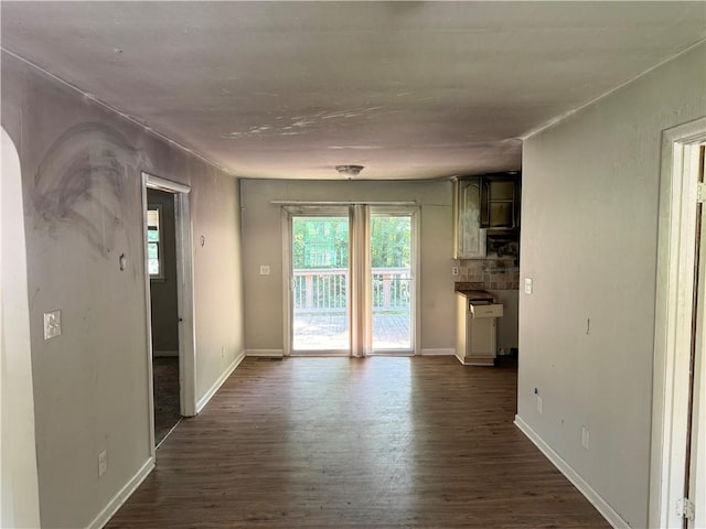 unfurnished living room featuring plenty of natural light and dark hardwood / wood-style flooring