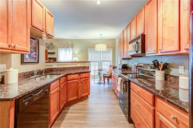 kitchen with a peninsula, light wood-style flooring, a sink, dark stone countertops, and black appliances