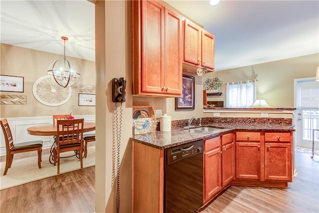 kitchen with light wood finished floors, a sink, dark stone counters, a chandelier, and dishwasher