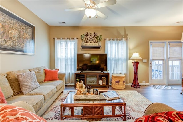 living area with visible vents, a ceiling fan, and wood finished floors