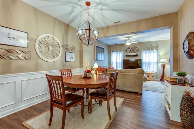 dining space featuring ceiling fan with notable chandelier and dark hardwood / wood-style flooring