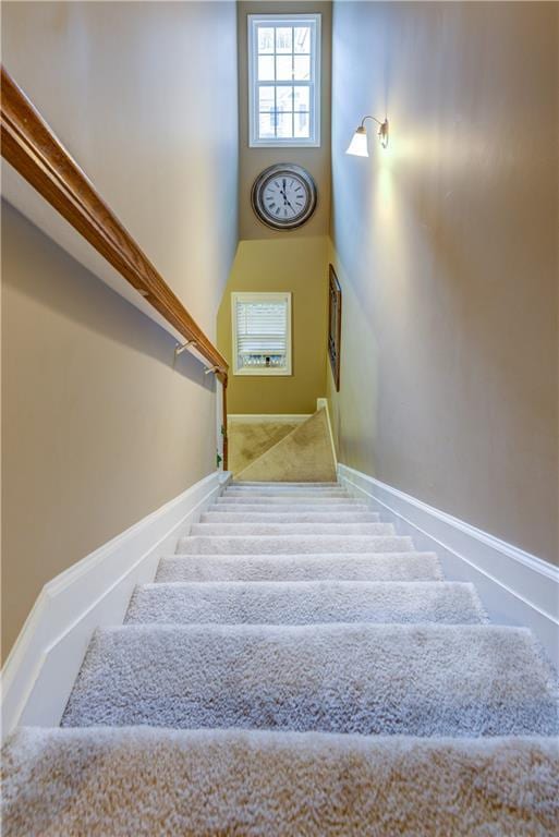 staircase featuring baseboards and carpet