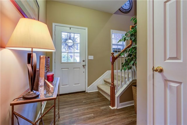 entryway featuring baseboards, wood finished floors, and stairway