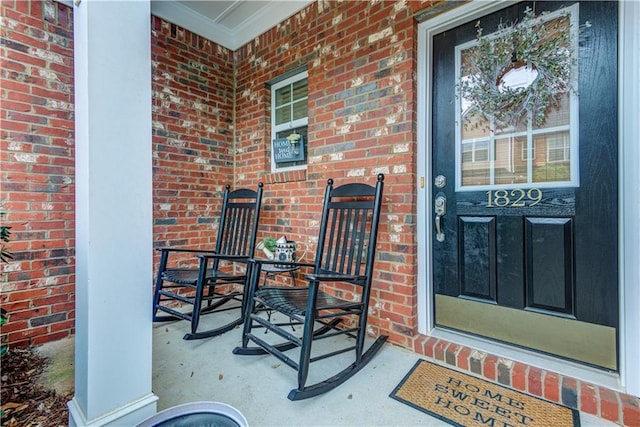 entrance to property featuring a porch and brick siding