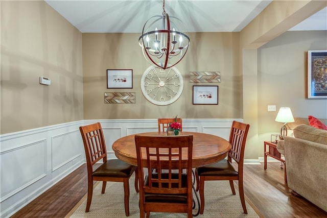 dining area with wood-type flooring and a notable chandelier