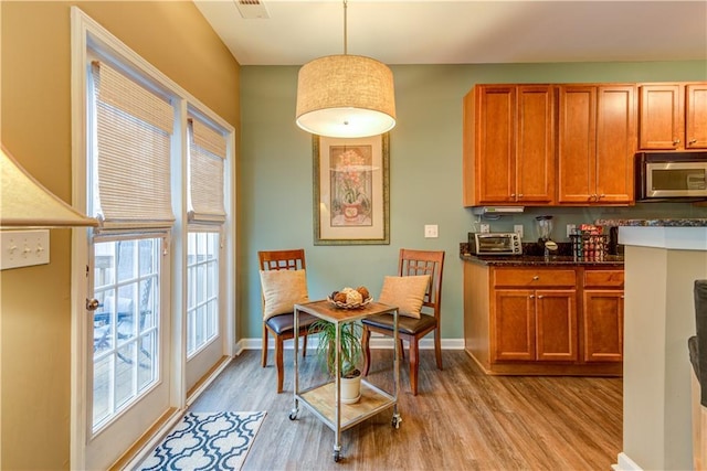 kitchen with light wood finished floors, baseboards, and stainless steel microwave
