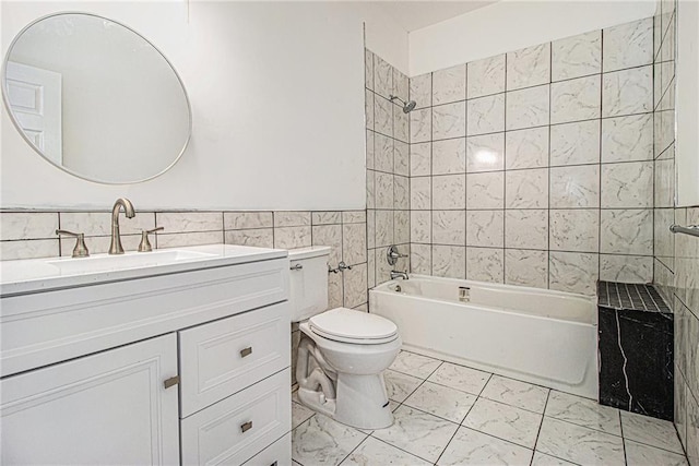 full bathroom featuring vanity, toilet, tiled shower / bath combo, and tile walls