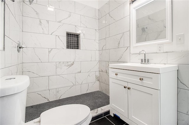 bathroom featuring vanity, tiled shower, tile walls, and toilet