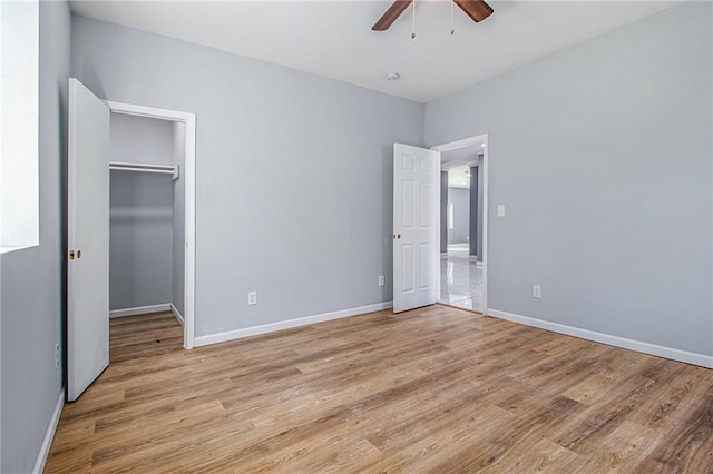 unfurnished bedroom with ceiling fan, a walk in closet, a closet, and light hardwood / wood-style flooring