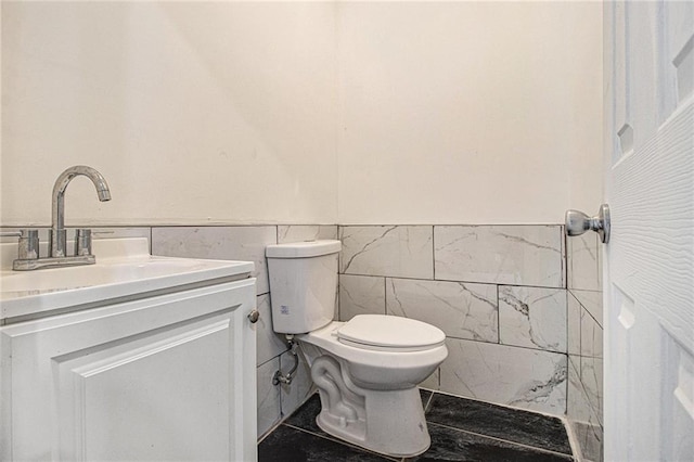 bathroom with vanity, toilet, and tile walls