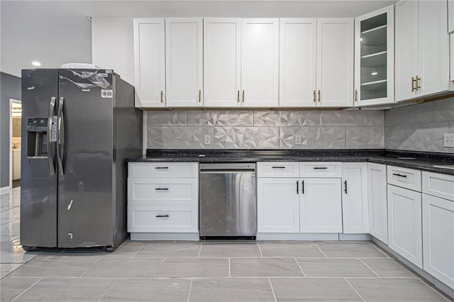 kitchen featuring white cabinetry, dark stone countertops, stainless steel fridge, and backsplash