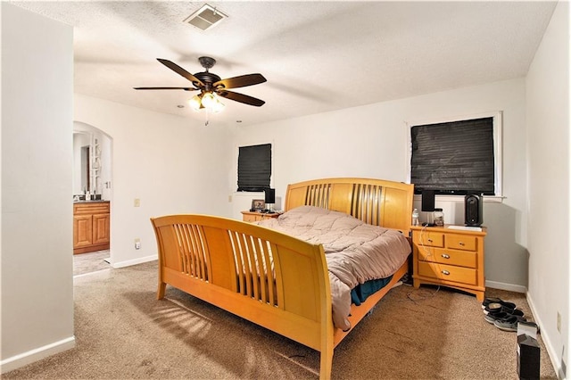bedroom with arched walkways, light colored carpet, visible vents, and baseboards