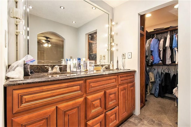 bathroom featuring a walk in closet, double vanity, recessed lighting, a ceiling fan, and a sink