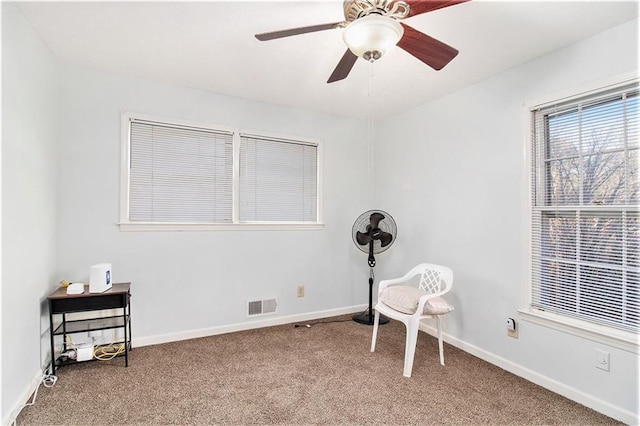 living area featuring carpet floors, baseboards, visible vents, and a ceiling fan