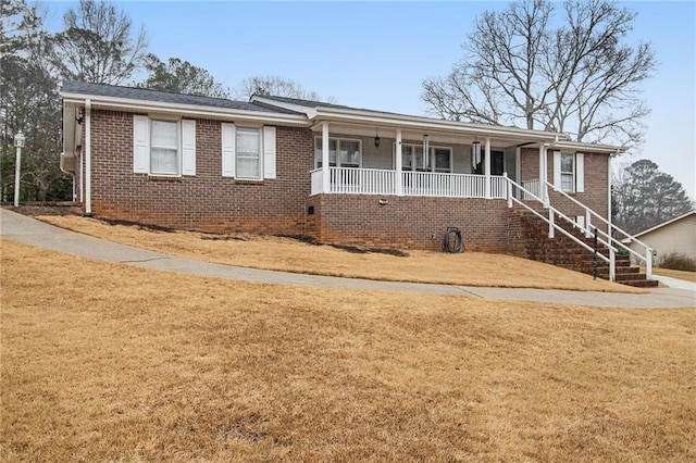 ranch-style house featuring covered porch, brick siding, a front lawn, and stairs