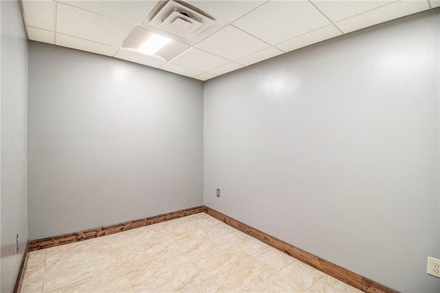 spare room featuring a drop ceiling, visible vents, and baseboards