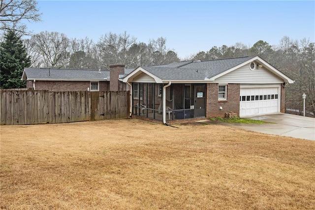 view of front of house with brick siding, fence, a sunroom, driveway, and a front lawn