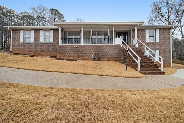 single story home with brick siding, a front lawn, a porch, and stairway