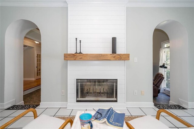 tiled living room with a large fireplace and crown molding