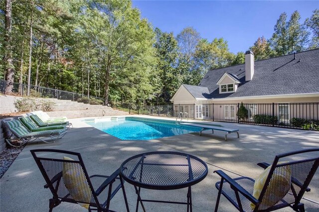 view of pool featuring a diving board and a patio