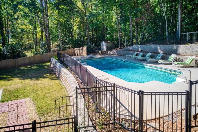 view of pool featuring a lawn, a patio area, and a shed