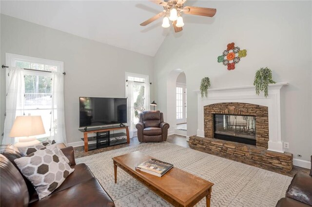 living room with ceiling fan, wood-type flooring, a fireplace, and high vaulted ceiling