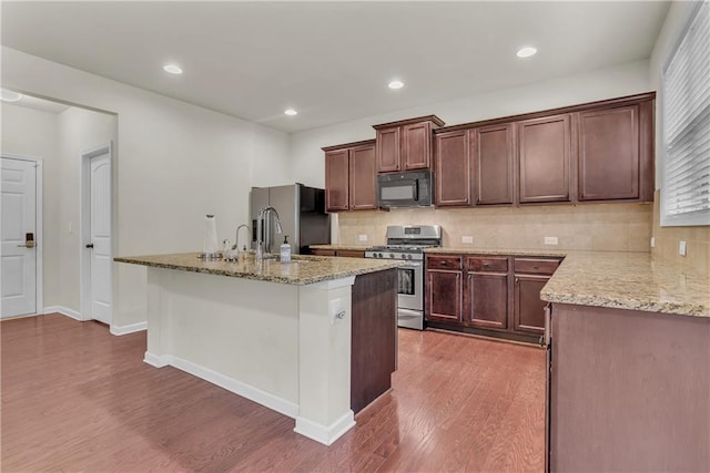 1354 Slate Bend Dr, Dacula, GA 30019 - kitchen with light stone counters, dark hardwood / wood-style floors, an island with sink, decorative backsplash, and stainless steel appliances