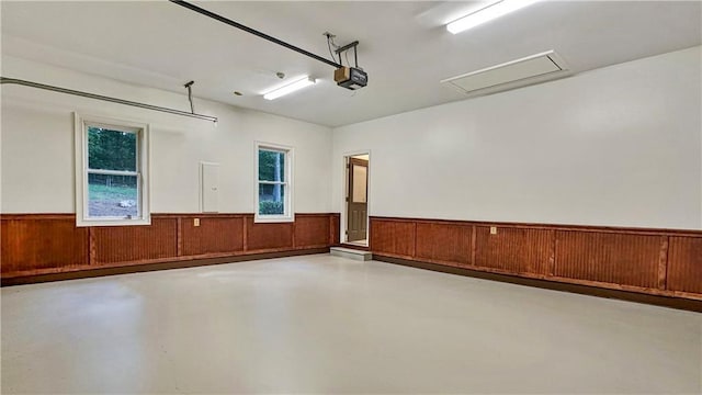 garage featuring a wainscoted wall, wooden walls, and a garage door opener