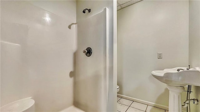 bathroom with walk in shower, tile patterned flooring, toilet, and baseboards