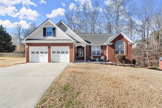 view of front facade with driveway, an attached garage, fence, and brick siding