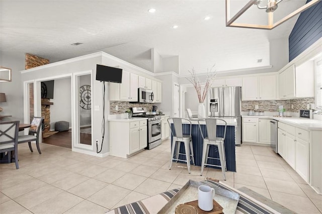 kitchen featuring light tile patterned floors, white cabinets, a kitchen island, appliances with stainless steel finishes, and light countertops