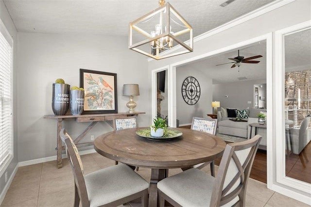 dining room featuring ceiling fan with notable chandelier, lofted ceiling, baseboards, and light tile patterned floors