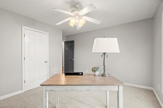 unfurnished office featuring light carpet, a ceiling fan, and baseboards