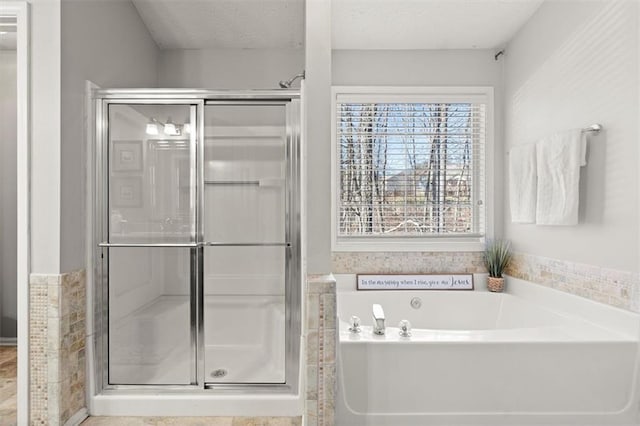 full bath with a stall shower, a garden tub, and a textured ceiling