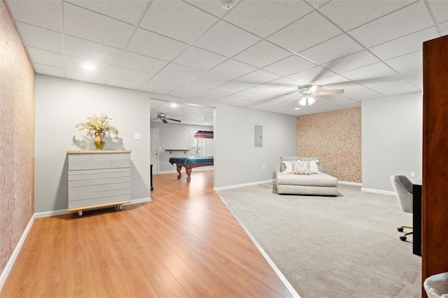 sitting room with baseboards, a drop ceiling, and wood finished floors