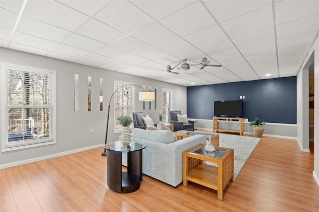 living room featuring a drop ceiling, wood finished floors, and a wealth of natural light