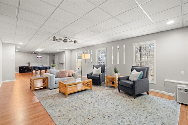 living room with a paneled ceiling, baseboards, and wood finished floors