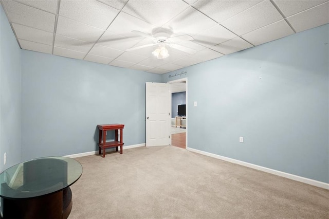 interior space featuring ceiling fan, a drop ceiling, carpet flooring, and baseboards