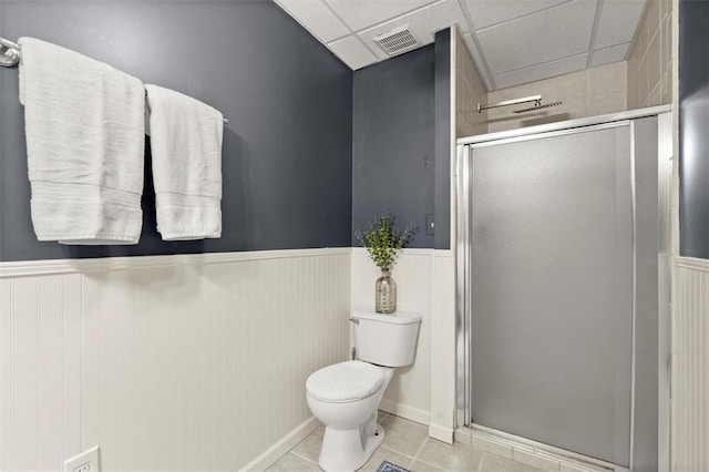 bathroom with toilet, a wainscoted wall, visible vents, a shower stall, and tile patterned floors