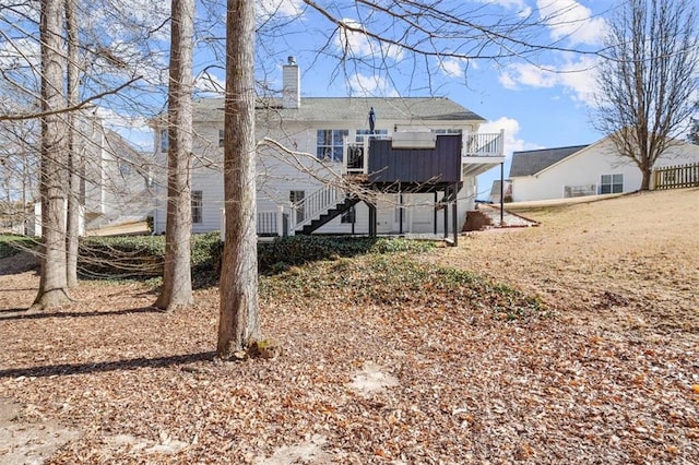 rear view of property featuring a chimney, stairway, and a wooden deck