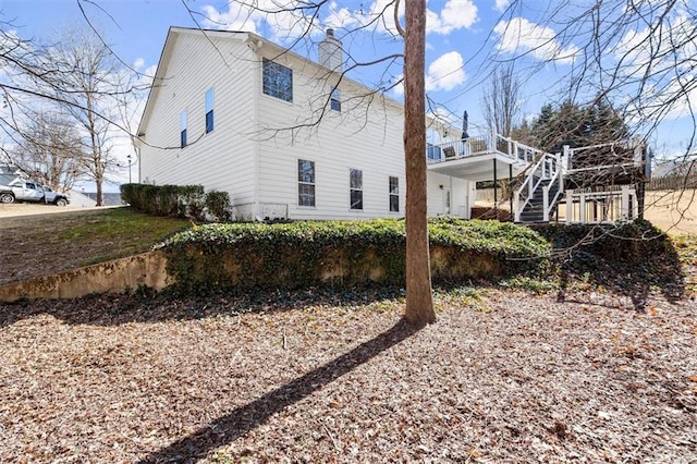 view of side of property with stairway, a chimney, and a wooden deck