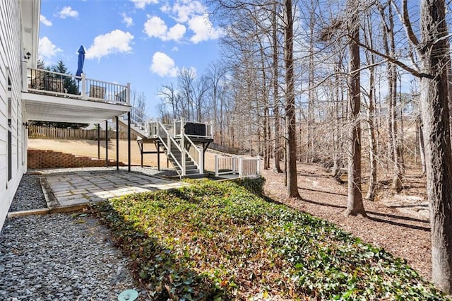 view of yard featuring stairway, a wooden deck, fence, and a patio