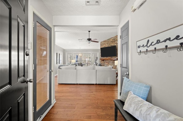 mudroom with visible vents, a ceiling fan, lofted ceiling, wood finished floors, and a textured ceiling