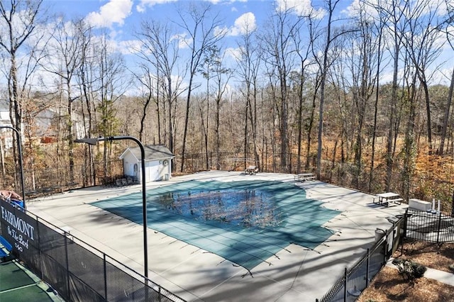 view of pool featuring an outbuilding, a patio, fence, and a fenced in pool