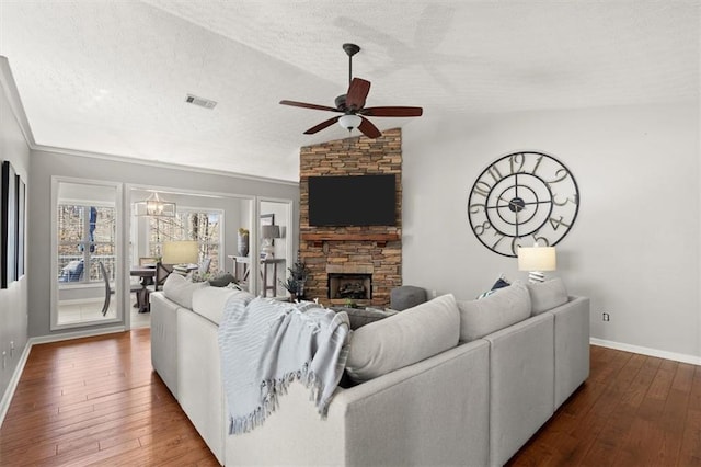 living area featuring a textured ceiling, lofted ceiling, a stone fireplace, wood finished floors, and visible vents