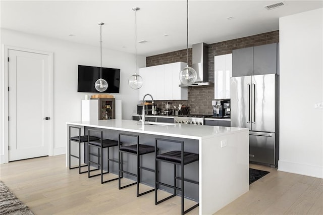788 W Marietta St Unit 1809, Atlanta, GA 30318 - kitchen featuring high end refrigerator, wall chimney exhaust hood, modern cabinets, light wood-style flooring, and a kitchen bar