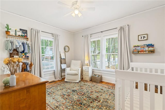 67 Trammell St SW, Marietta, GA 30064 - bedroom featuring a crib, crown molding, wood finished floors, baseboards, and a ceiling fan